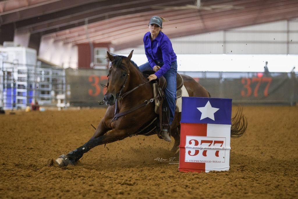 Cowgirl barrel racing in a purple moisture wicking shirt
