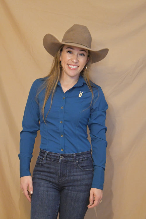 Woman wearing a blue long-sleeve button-up shirt with a collared neckline, styled with a cowboy hat and jeans.