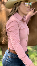 Woman in pink shirt and cowboy hat standing next to a horse