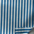 Teal and white striped fabric shown close up with a ruler on the right side for scale.
